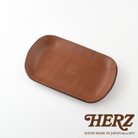 職人手作皮革小物收納盤，淺棕色，以車縫線勾勒邊緣，中央壓印有「HERZ MADE IN JAPAN」字樣。