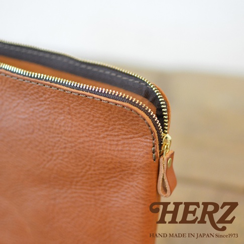 職人手作皮革Organ雙拉鍊收納袋，採用棕色皮革材質，配有金色拉鍊和同色系皮革拉頭。袋身紋理清晰，質感自然。