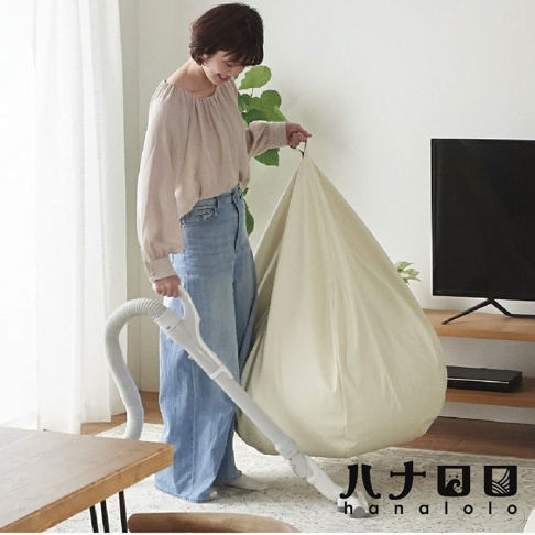 一位女性手持吸塵器，正在清潔一個淺米色的巨大懶骨頭沙發。