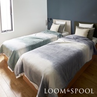 兩張單人床分別覆蓋著淺綠色與灰色漸層的短絨舒柔單人毯，毯子觸感輕柔，呈現自然的暈染效果。