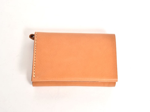 職人手作皮革中型雙折短夾，溫潤的淺棕色皮革，縫線精緻，一側有小巧的皮革掛環。