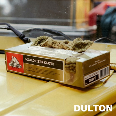 黃色車蓋上放置一盒橄欖綠色的DULTON超細纖維萬用擦拭布，盒身印有大象圖案的FOR CAR LIFE品牌標誌，一塊擦拭布正從盒裝頂部抽出，背景可見汽車擋風玻璃雨刷。