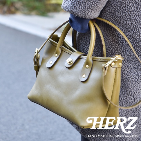 橄欖綠皮革迷你托特包，帶有頂部提把、可拆卸肩帶和金色金屬旋轉鎖扣。