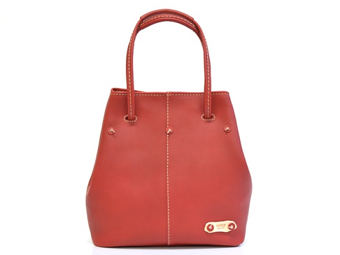 紅色皮革托特包，有兩條手提把，包身中央有縫線裝飾，兩側有金屬卯釘，底部右側有金色品牌標誌。