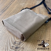 淺色帆布平板收納側背包，附黑色背帶，放置於木紋桌面。