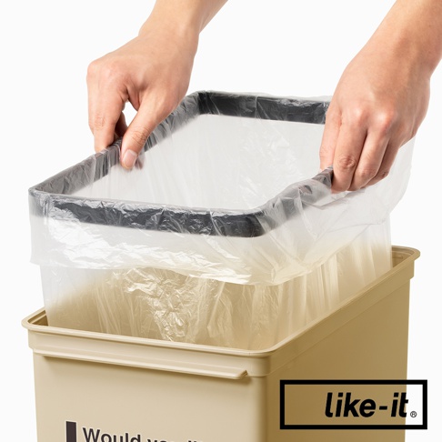 雙手正在為一個淺米色方形垃圾桶套上透明垃圾袋，垃圾桶邊緣有一個黑色內框。