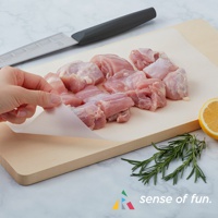 捲筒式砧板保潔墊片，半透明材質，帶有網格紋理，鋪設在木質砧板上，上方擺放著切塊的生雞肉、一把刀、檸檬和迷迭香。