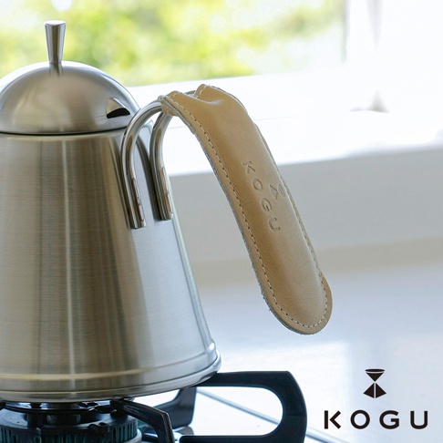 日製咖啡壺握柄專用植鞣皮革隔熱套，淺棕色皮革，壓印 KOGU 品牌標誌，附有縫線裝飾，套在銀色金屬壺把上。