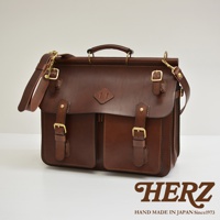 深棕色皮革旅行包，配有可調節肩帶、頂部提把、黃銅色鎖扣和兩個前置口袋。