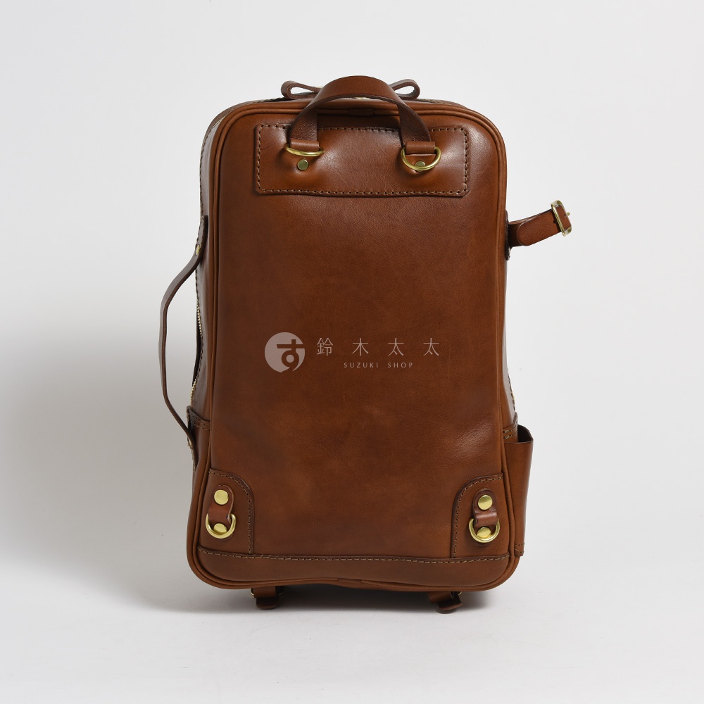 棕色皮革手作兩用多功能後背包，正面中央有品牌標誌，兩側有側面口袋，頂部有提把和可調節肩帶。