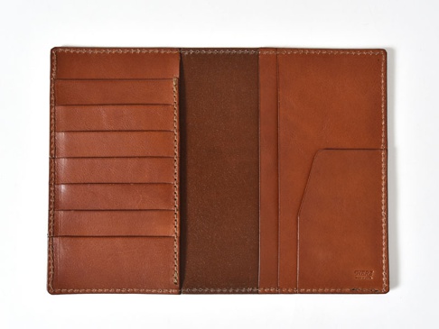 職人手作皮革多用途收納長夾，淺棕色皮革，攤開內裡，左側有六個卡槽，右側有兩個直插式夾層，內部為深棕色皮革，右下角壓印品牌標誌。