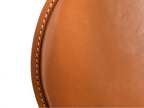 職人手作皮革圓形坐墊 (KZ-6)，採用溫暖的棕褐色皮革，表面呈現細緻紋理，邊緣以米白色線條進行手工縫製，展現精緻工藝。