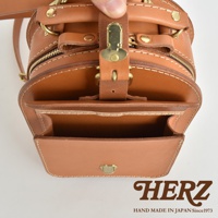 職人手作皮革迷你後背包，展示了皮革的自然紋理和精緻縫線。包款採用棕色皮革，搭配黃銅色金屬扣環和拉鍊，結構精巧，展現復古風格。