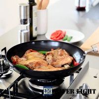 黑色不易生鏽平底鍋，鍋內有烹煮中的雞肉塊、青椒和紅椒，鍋柄為木質，置於瓦斯爐上。