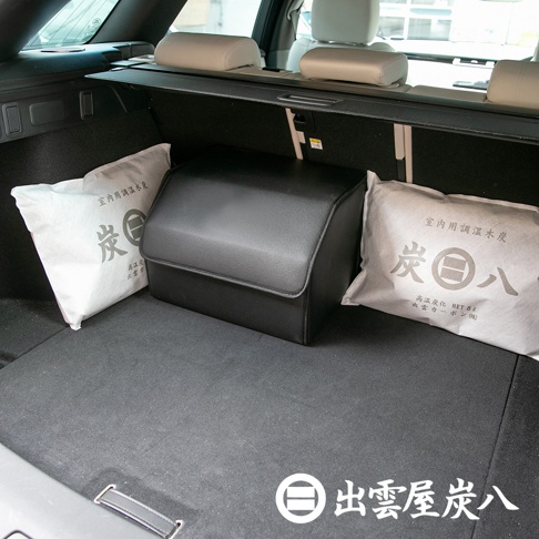 車廂內部，黑色皮革收納盒置於中央，左右兩側各有一個白色布袋，袋上印有「炭」字及日文說明，內容物為調濕木炭。