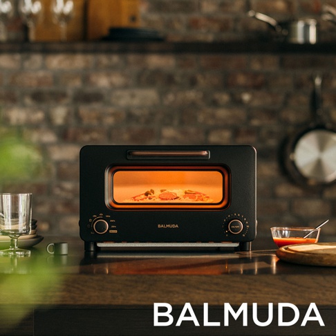 The Toaster Pro 蒸氣烤麵包機 K11C-SE 專業版，採用黑色霧面金屬外殼，搭配玫瑰金色的提把，簡潔的設計風格。烤箱內部有正在烘烤的食物，玻璃門清晰可見。