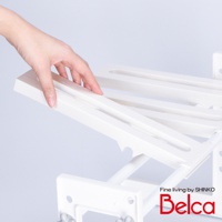 白色塑膠伸縮槽下雙層L腳收納架，結構由多層白色塑膠板和金屬管組成，手部正在調整其中一層板。