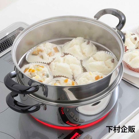 不鏽鋼雙層蒸鍋，上層裝有七個紙杯裝的蒸製點心，部分點心內含南瓜丁或玉米粒。鍋身帶有兩個黑色隔熱提把，置於電磁爐上，爐面發出紅色光暈。