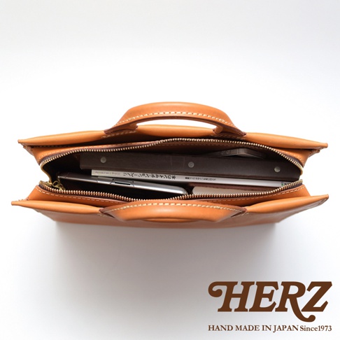 HERZ 職人手作皮革公事包，棕色皮革材質，俯視視角，展示包內物品。