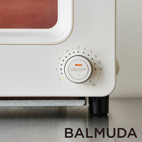 白色蒸氣烤麵包機的特寫，顯示其側面的圓形控制旋鈕，旋鈕上有數字刻度和「ON/OFF」字樣。烤麵包機外觀簡潔，材質為光滑的烤漆。