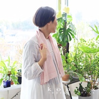 MOKU ORGANIC 有機棉食材染料長毛巾，淡粉色，材質柔軟，帶有細條紋紋理，圍繞在一位女性頸部。