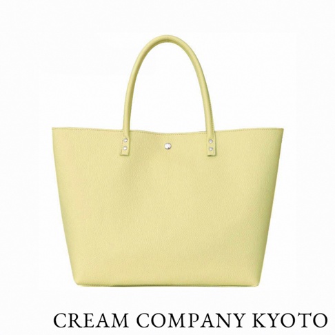 這是一款由 CREAM COMPANY KYOTO 出品的鵝黃色簡約皮革托特包，採用輕量耐用的牛皮革製作，正面設有金屬鉚釘與按扣裝飾，呈現出簡潔俐落的日式職人手作風格。
