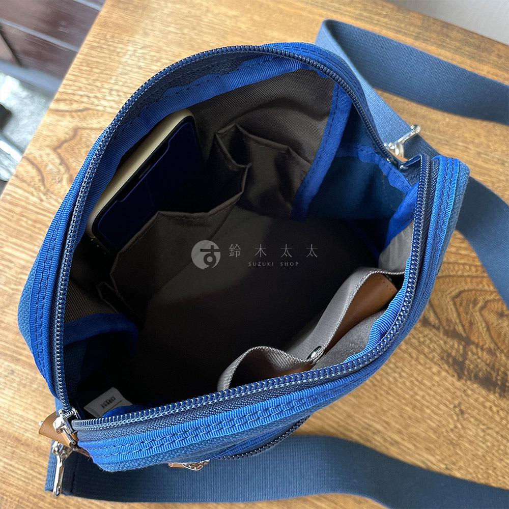 石洗帆布散步包內部，可見手機置於外層隔袋，內部有兩個小隔袋，以及一個較大的開放式隔間。