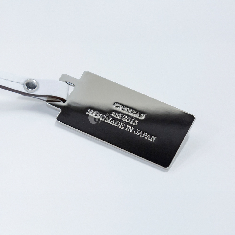 JETTER 迷你箱型包 CJTF-038 吊牌，銀色金屬材質，印有黑色字體「CREZZAN est 2015 HANDMADE IN JAPAN」，搭配白色皮革繫帶。