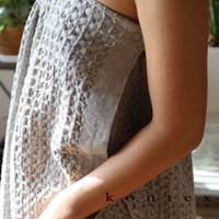 QULM 棉麻混紡平口鬆緊浴巾浴裙，呈現蜂巢格紋織紋，淺灰色調，配有兩個同色系按扣，材質觸感自然。