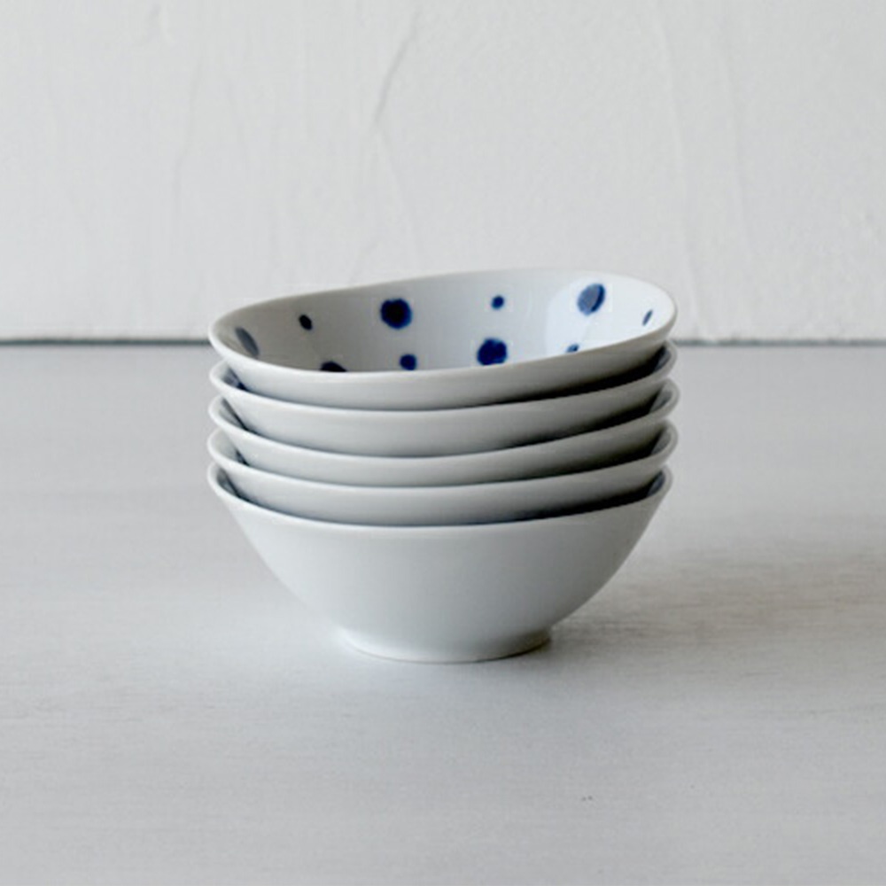 疊放的五個白色陶瓷小菜碟，其中最上方的碟內側印有藍色圓點圖案。