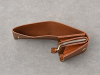 職人手作皮革Organ雙折迷你短夾，採用棕色皮革，呈現雙折設計，內含拉鍊零錢袋及卡片夾層，並以金屬釦固定。