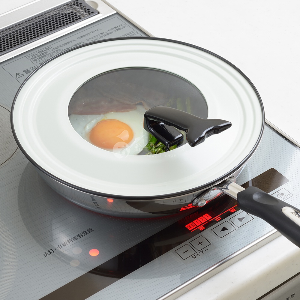 可立式強化玻璃鍋蓋，擁有白色邊緣與黑色把手，鍋蓋中央為透明玻璃，可見鍋內煎蛋和蔬菜。