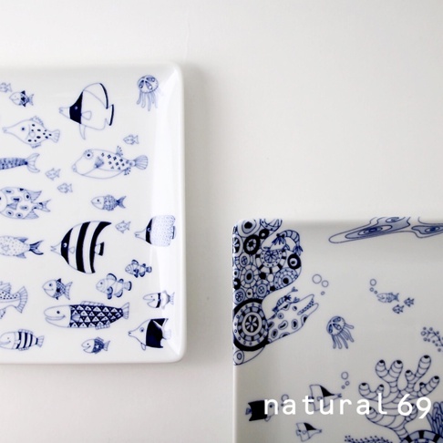 兩個白瓷方形餐盤，其中一個佈滿藍色線條繪製的各種魚類和水母圖案，另一個餐盤角落有藍色線條繪製的機械風格海洋生物和珊瑚。