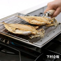 瓦斯爐專用炭烤風萬用燒烤盤，不鏽鋼材質，黑色爐架上放置著兩條烤製金黃的魚，下方有藍色火焰，右上角有一隻手持木柄的夾子。