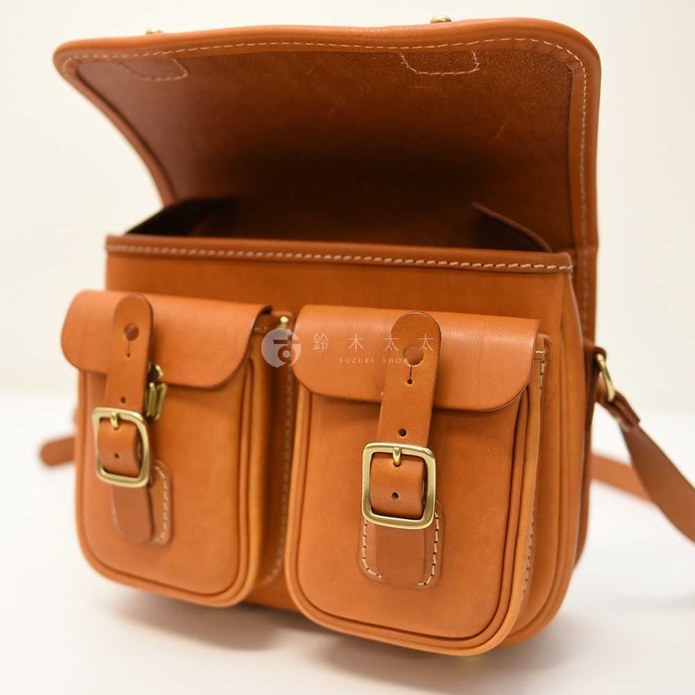 日本HERZ 職人手作皮革經典雙扣郵差包 CK-100，棕色皮革，設有兩個前袋，配有黃銅釦環和皮帶。