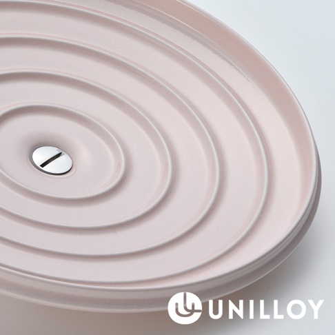 淺粉色琺瑯鑄鐵鍋鍋蓋，鍋蓋表面有同心圓紋路，中央設有銀色金屬把手。