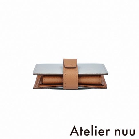 Atelier nuu 品牌，一個雙折短夾，由淺藍色和棕色皮革製成，並有一個棕色皮革帶固定。