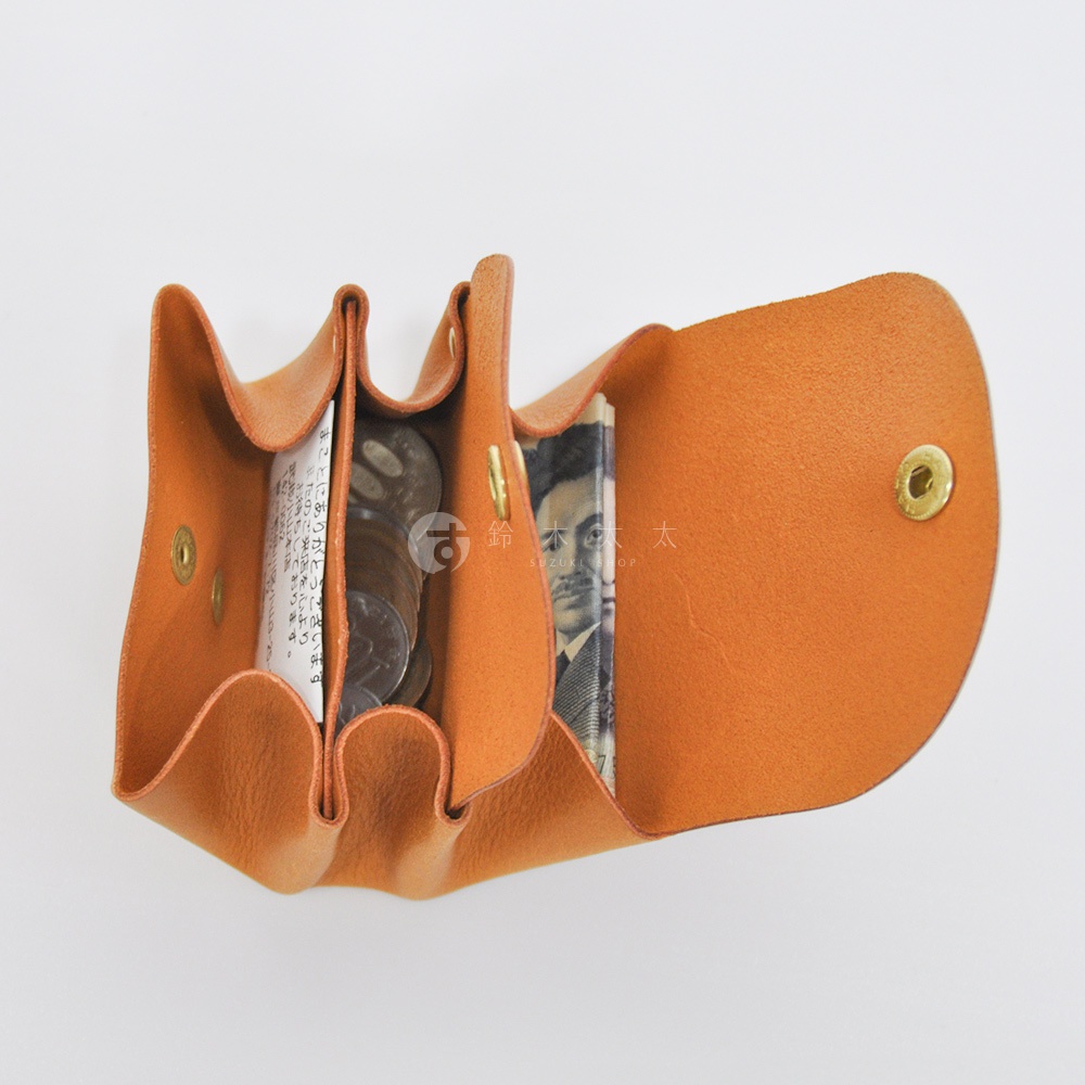 橘色皮革三層收納零錢包，內含日圓紙鈔與硬幣，以金屬按扣固定。
