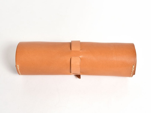 職人手作皮革捲捲收納筆袋，採用光滑淺棕色皮革製成，整體呈圓筒狀，以皮革帶固定。