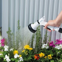 手持白色蓮蓬頭，對著一叢綠葉和五顏六色的花朵噴灑細水流，蓮蓬頭上有藍色標誌。