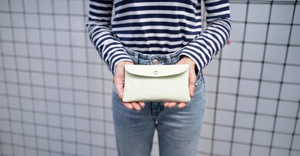 淺綠色皮革手拿包，帶有銀色按扣，設計簡約，適合日常使用。