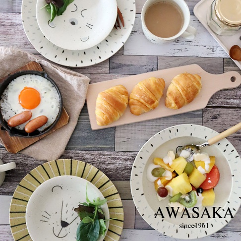 陶瓷餐盤組，包含繪有刺蝟圖案的盤子，以及裝有水果優格和牛角麵包的盤子，整體為白色與淺木色調。