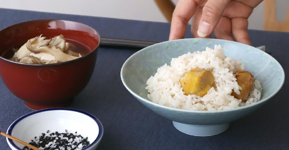 一組紅底、淺藍底的日式茶碗，分別盛有香菇湯和栗子飯，旁邊還有小碟芝麻鹽。