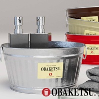 OBAKETSU 手工製金屬水桶，裝有兩個銀色皂液器，旁邊疊放著毛巾。