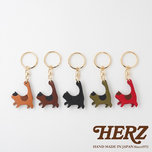 五個皮革貓咪造型鑰匙圈，分別為棕色、深棕色、黑色、軍綠色和紅色，每個鑰匙圈都有金色的圓形鑰匙環和扣環。