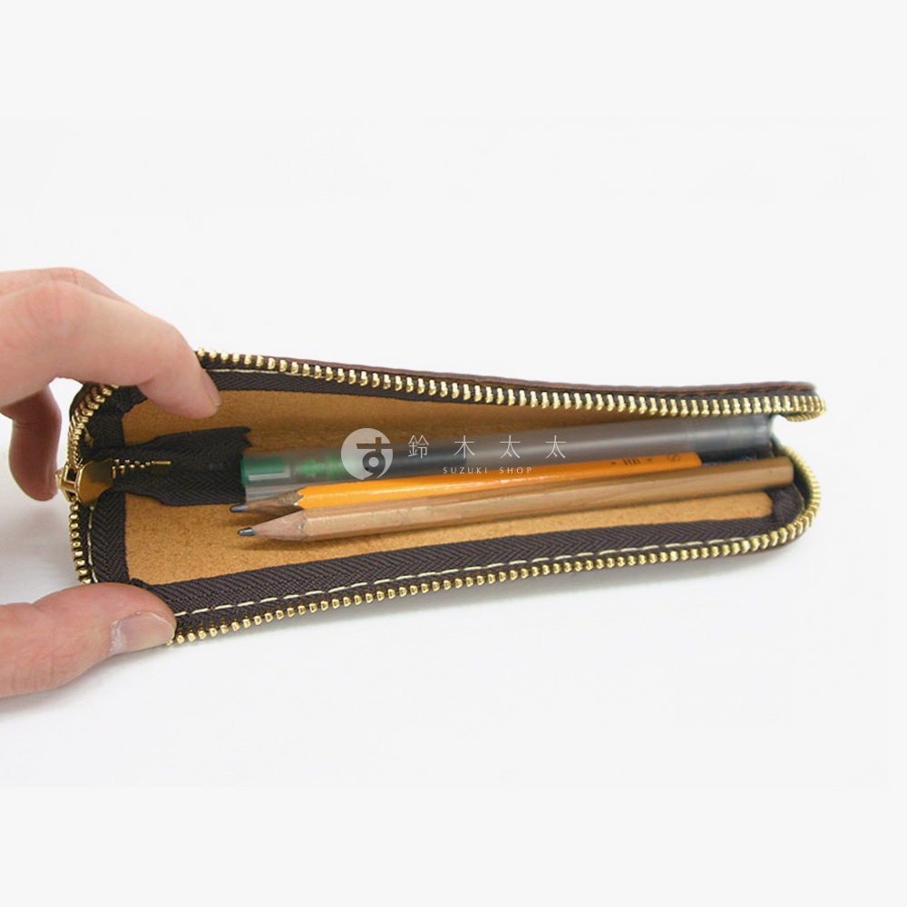 手持打開的棕色皮革筆袋，內有鉛筆和筆。