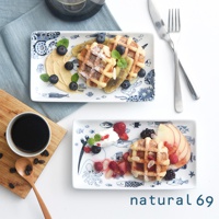 兩個cocomarine長方餐盤，盤底有藍色海洋生物與魚類圖案。上方餐盤盛有鬆餅、香蕉片、藍莓與花生醬。下方餐盤盛有鬆餅、覆盆子、草莓、藍莓、鮮奶油與水蜜桃切片。