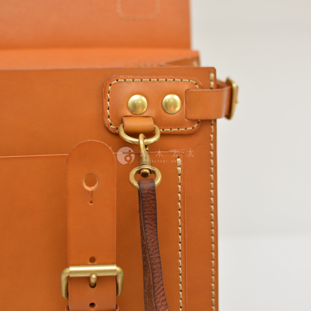 職人手作皮革旅行包A-102，特寫展示包款的棕褐色皮革材質、金屬釦環、卯釘及縫線細節。