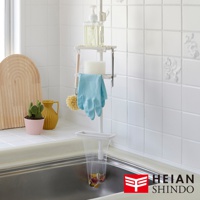 白色直撐式濾網架，上方掛有洗碗精瓶、海綿、藍色手套和清潔刷，下方則掛有裝有廚餘的濾網袋，架子立於廚房水槽旁。