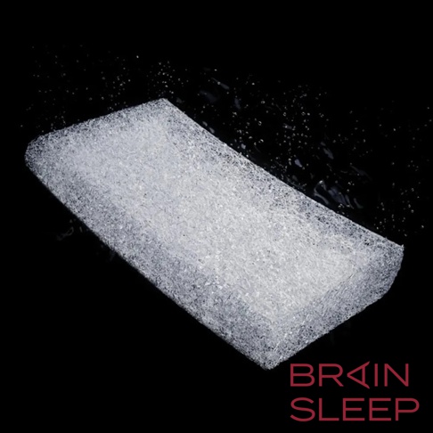 白色網狀材質的腦眠科技枕，置於黑色背景上，部分區域有水珠反光。